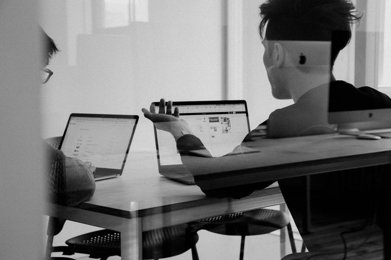 Two people talking with laptops
