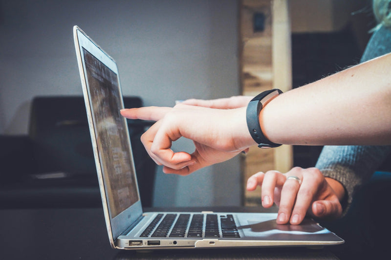 Two people working at a laptop and pointing